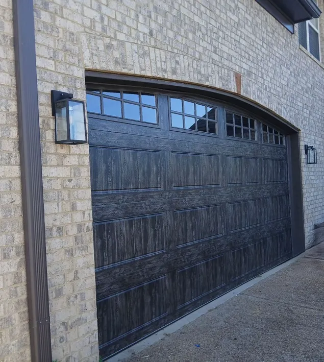 Arched black garage door on a brick home