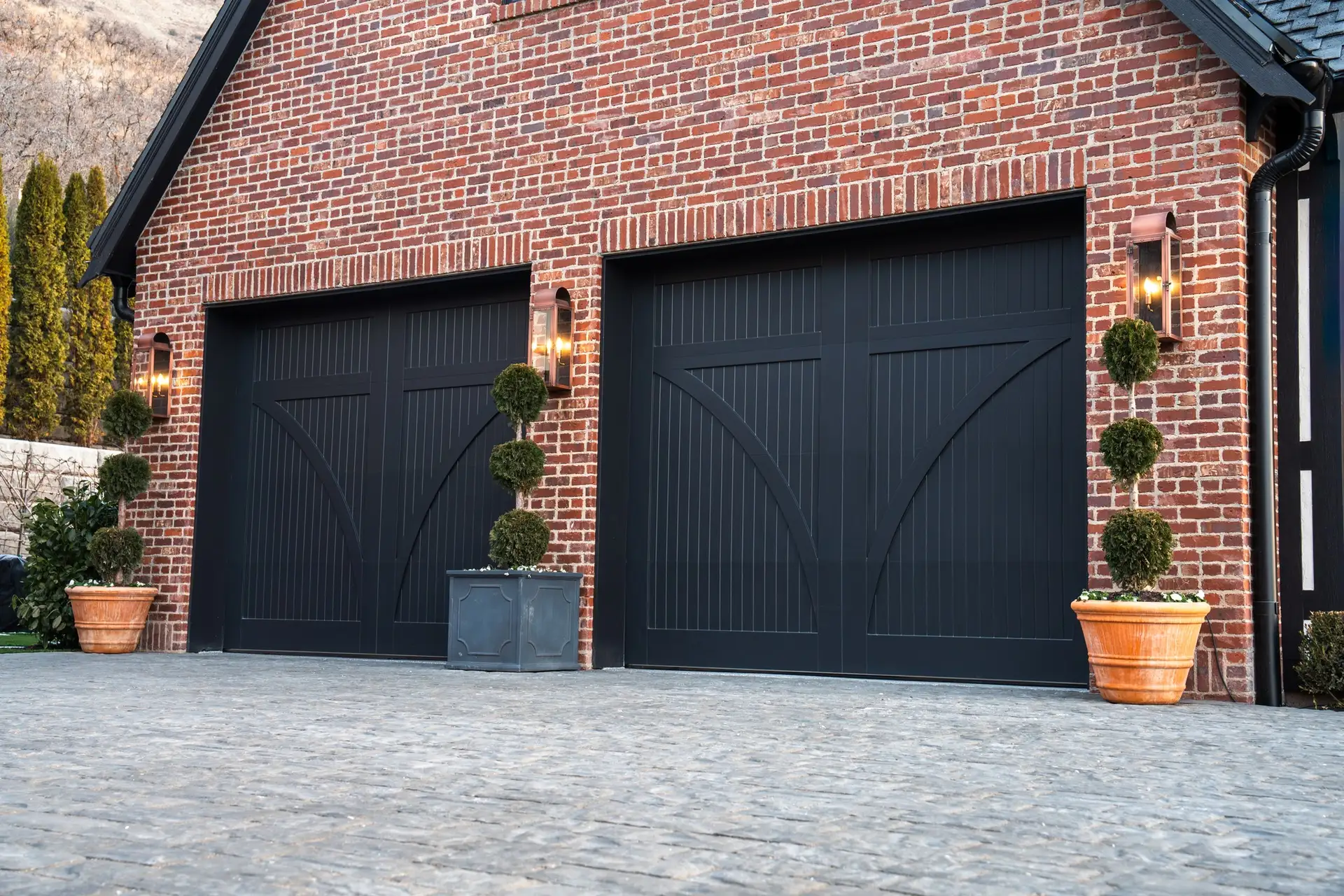 Black carriage-house garage doors on a brick home