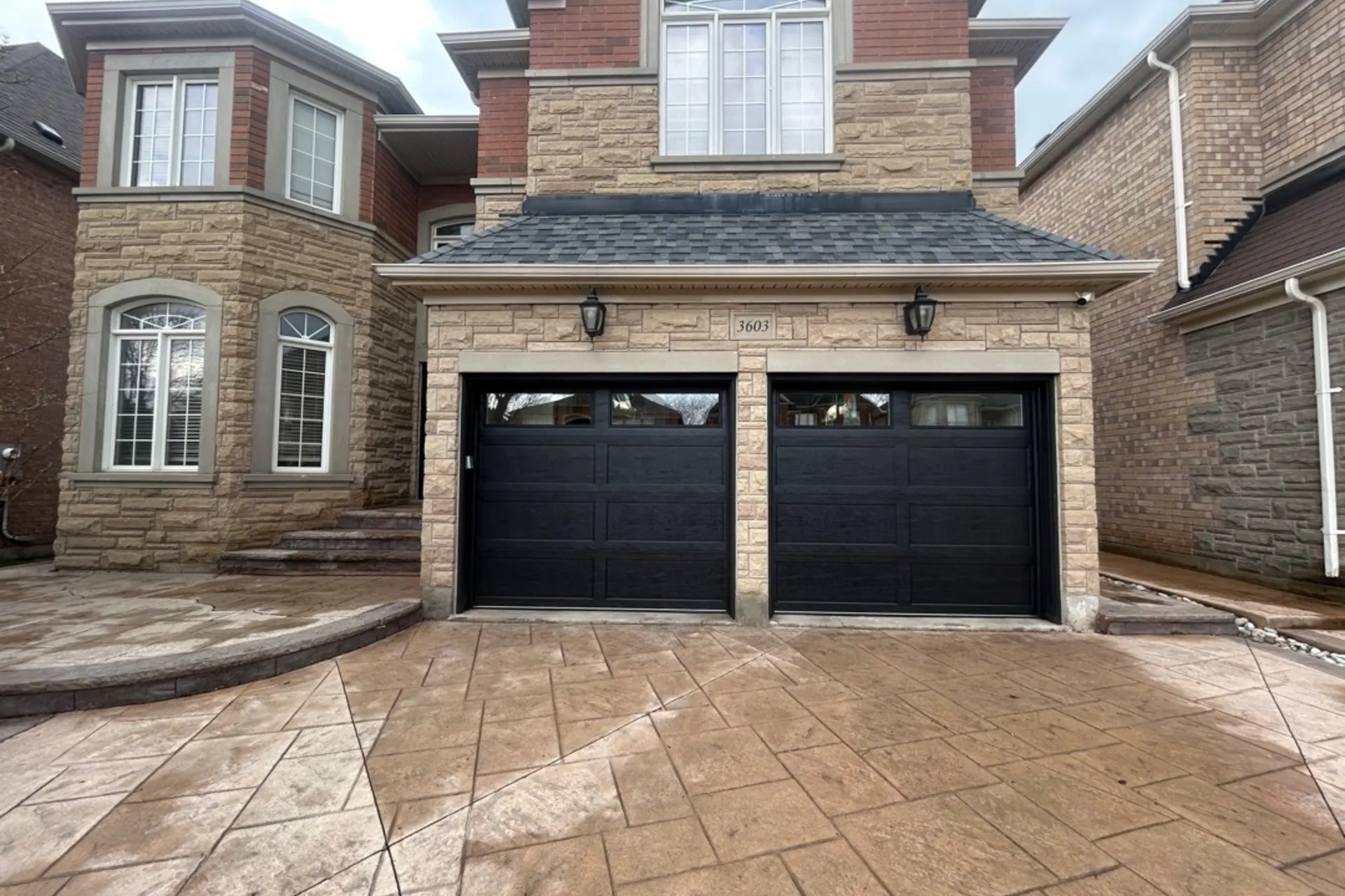 Black two-car garage doors on a stone home in Costa Mesa