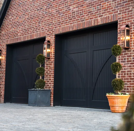 Finished black carriage garage doors on a brick home