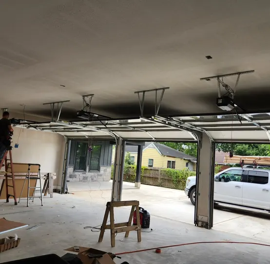 Technician inspecting garage door tracks and opener