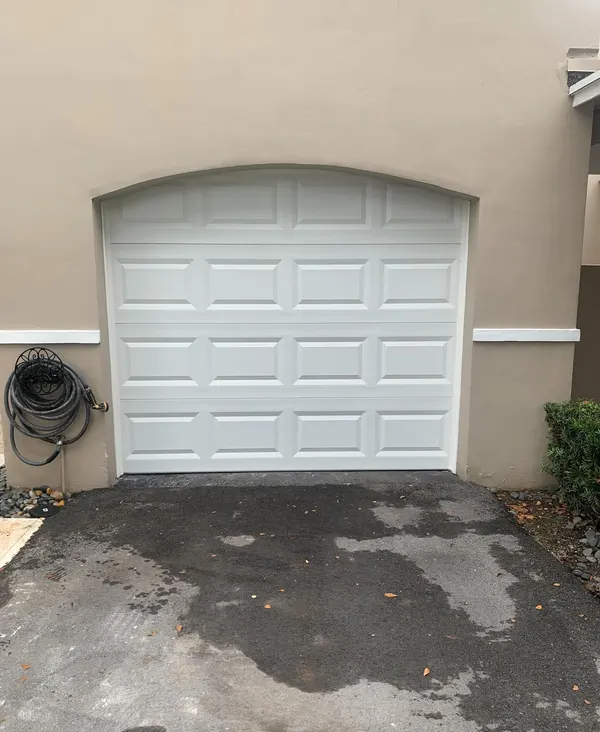 White arched raised-panel garage door on a stucco home