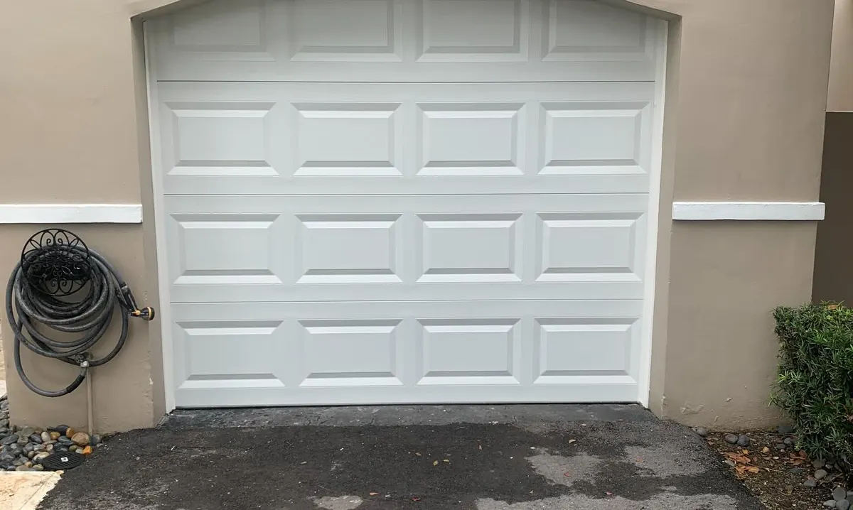 White arched raised-panel garage door on a stucco home