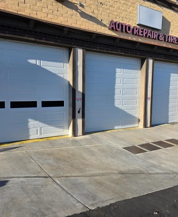 Three white sectional doors on an auto repair shop