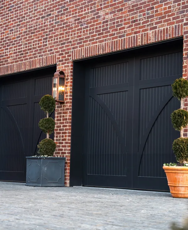 Black carriage-house garage doors on a red brick home