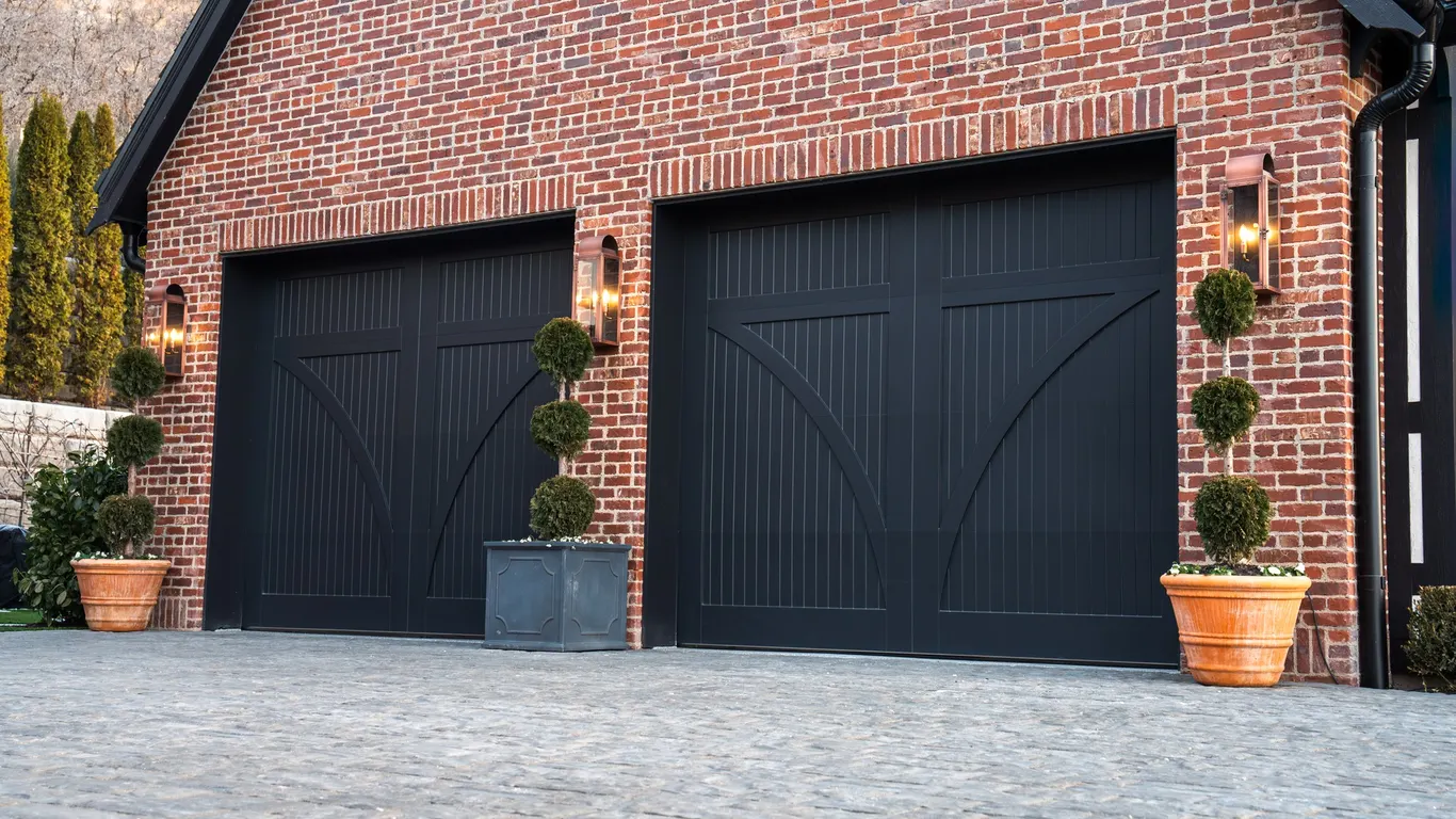 Black carriage-house garage doors on a red brick home