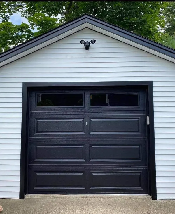 Black carriage-style single garage door on a white detached garage