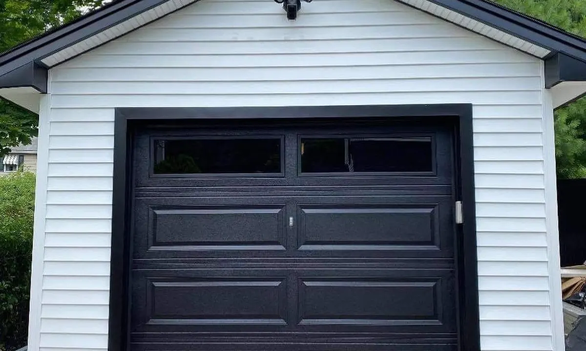 Black carriage-style single garage door on a white detached garage