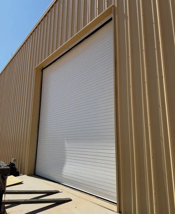 White rolling steel door on a tan metal building