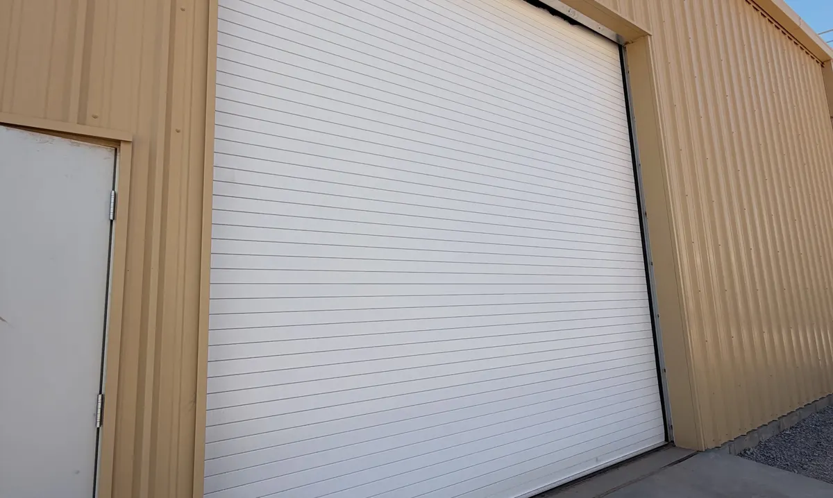 White rolling steel door on a tan metal building