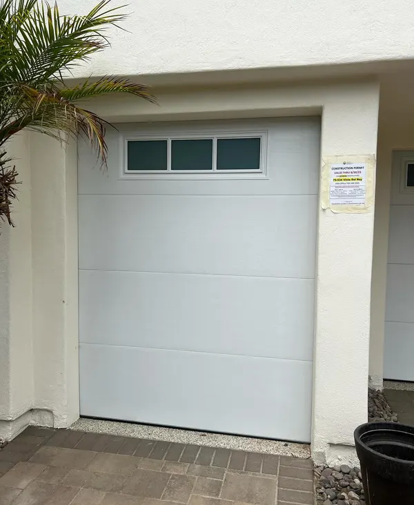 White insulated double garage door with windows over pavers