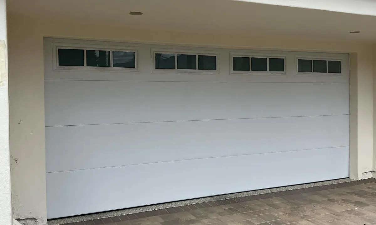 White insulated double garage door with windows over pavers