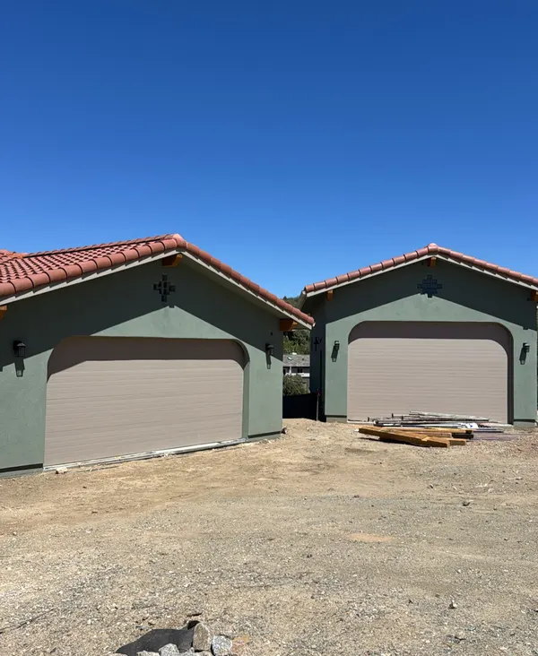 Two new detached garages with garage doors on a construction site