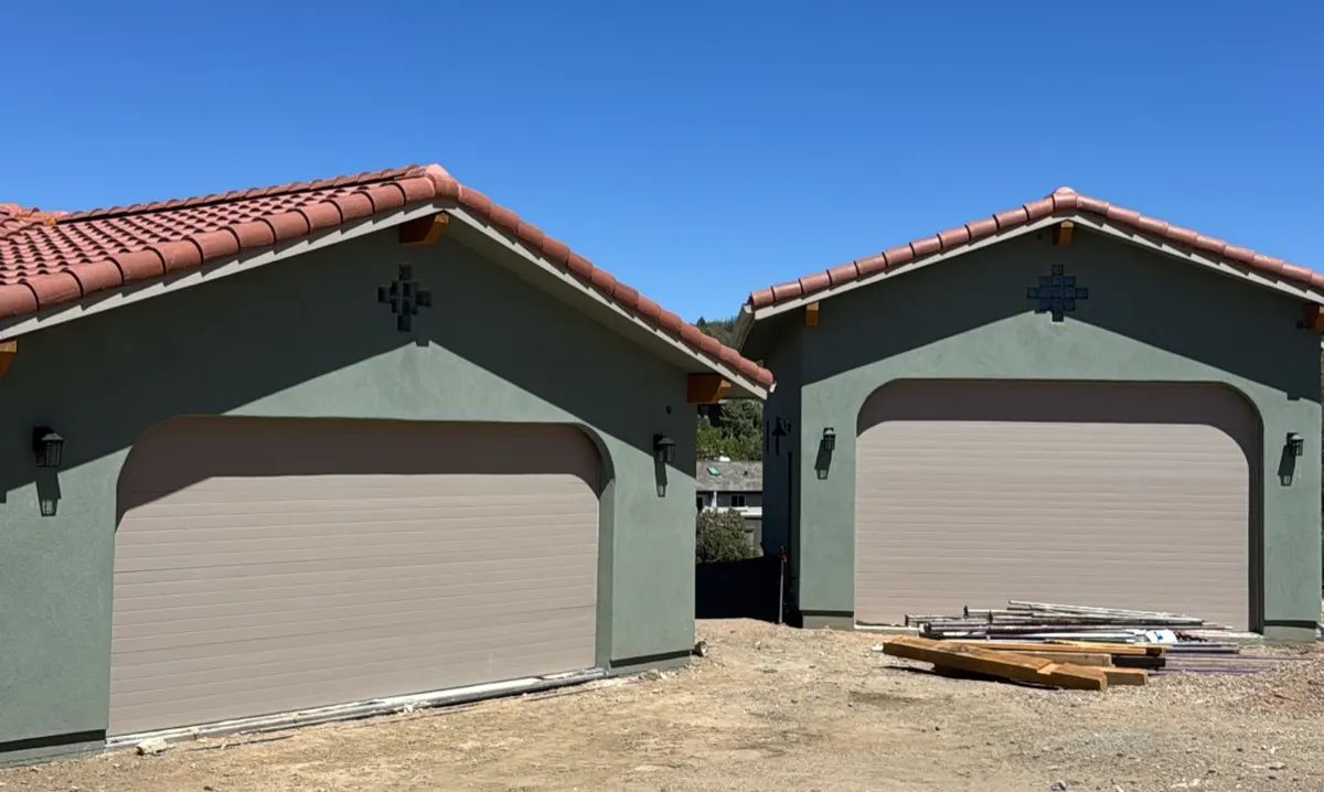 Two new detached garages with garage doors on a construction site