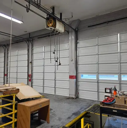 Inside an auto shop service bay with sectional doors and operators