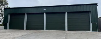 Row of green commercial roll-up doors on a steel building