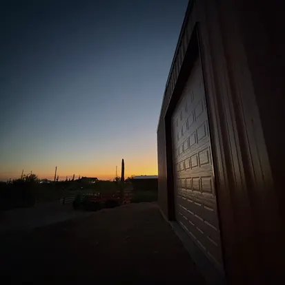 Roll-up garage door on a steel building at sunset