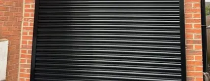 Black roll-up garage door on a brick building