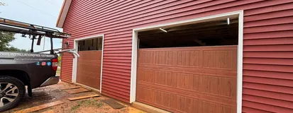 Wood-look garage door installed on a red barn-style garage
