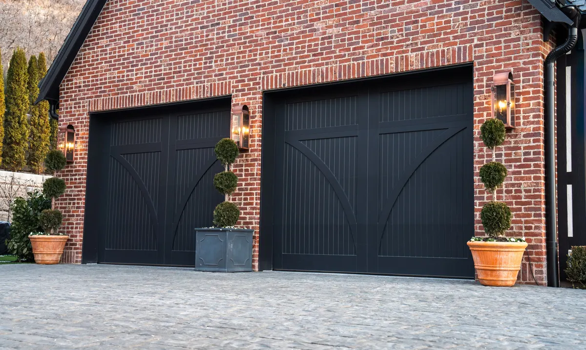 New black carriage-house garage doors installed on a brick home