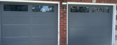 Two gray garage doors with window tops after maintenance