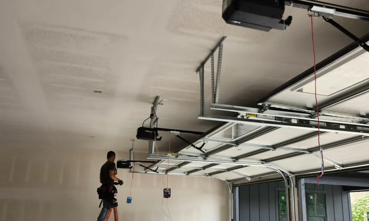 Technician installing a garage door opener on the ceiling