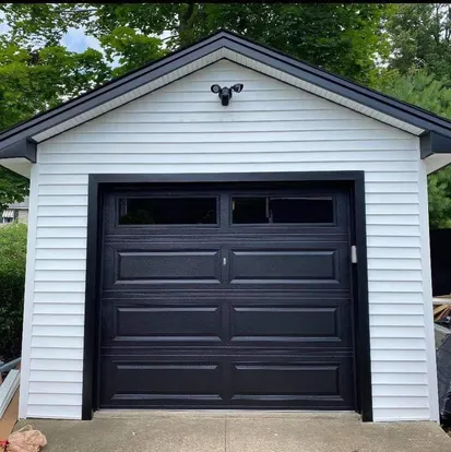 Black carriage-style single garage door after section replacement