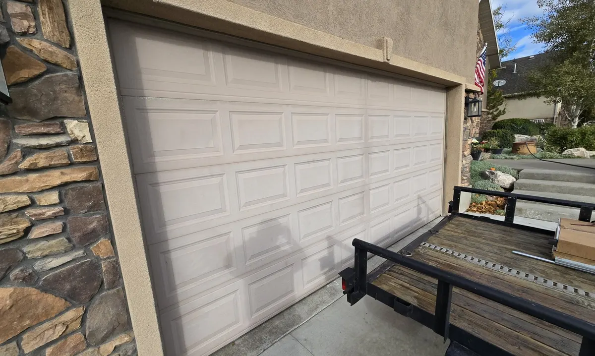 Two-car garage door with a dented lower panel before replacement