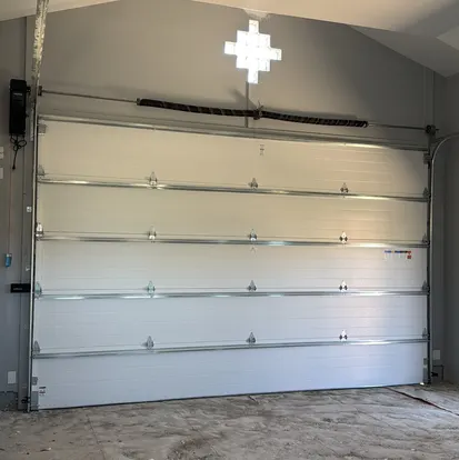 Insulated garage door with torsion spring above the opening
