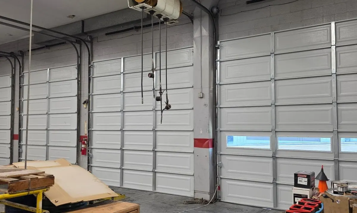 Garage door tracks and cables being realigned in a service bay